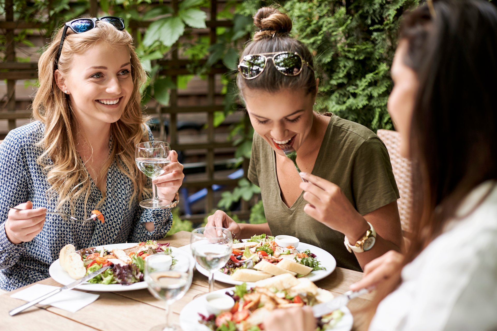 Przyjaciółki jedzą lunch w ogródku restauracji